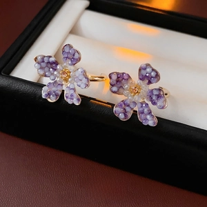 Vintage C-shaped floral earrings with purple beads and orange crystals on a jewelry box