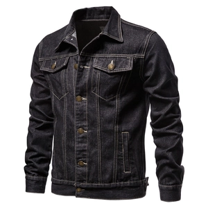 Detailed close-up of stitching and metal button on men's dark denim jacket pockets
