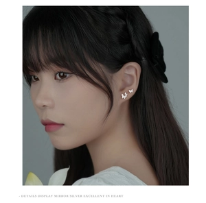 Detail view of butterfly ear studs with silver diamond-set design on model's ear