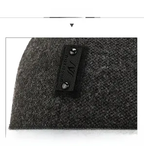 Dettaglio del tessuto in maglia grigio scuro con etichetta in pelle nera e rivetti
