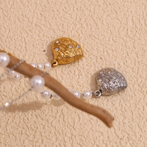Detail of 18K gold and silver heart pendants with rhinestones on a pearl chain