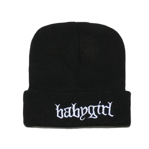 Dettaglio del ricamo Babygirl su un berretto in maglia nera con contorno azzurro