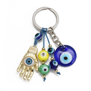 Macro shot of gold Hamsa Hand keychain with blue Evil Eye charms and colorful beads