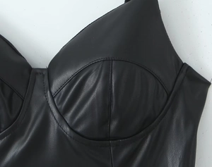 Detalle del corpiño negro de cuero sintético con textura suave y costuras curvadas