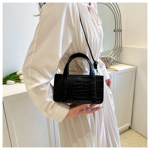 Detail showing elegant black crocodile embossed texture on a compact crossbody handbag