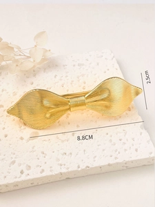 Detailed view of golden bow hair clip with textured metal finish measuring 8.8cm in length