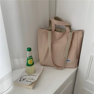Detalle de bolso tote de lona con correa de cuadros rosa y verde en el alféizar