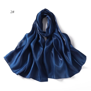 Macro detail of glossy dark blue silk scarf fabric showing soft texture and sheen