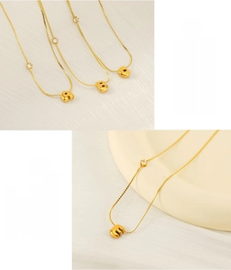 Detail of gold bubble letter pendants on stainless steel necklaces with white zircon stones