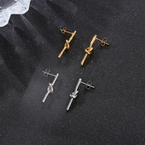 Boucles d'oreilles nœud minimalistes en acier titane, finitions or et argent sur fond noir