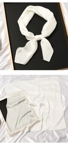 Detail of elegant white silk scarf on luxury black tray and draped on satin fabric