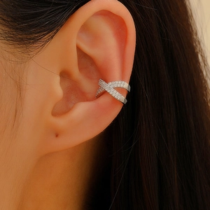 Detailed view of a silver X-shaped ear cuff with sparkling cubic zirconia on an ear
