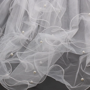 Close-up of white bridal veil mesh with delicate handmade pearls and soft lighting