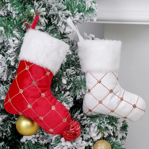 Classic red and white sequined Christmas stockings with plush trim on a snowy tree