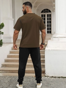 Outdoor back view of men's dark brown short sleeve t-shirt and black joggers set