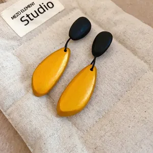 Minimalist irregular oval wood drop earrings in black and gold on quilted fabric