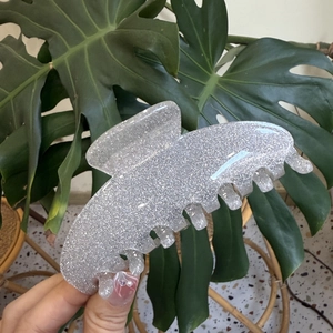 Close-up of a silver glitter acrylic hair claw clip with a glossy sequin finish