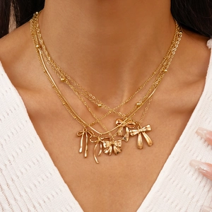 Détail d'un collier multicouche doré avec cinq pendentifs élégants en forme de nœud 3D