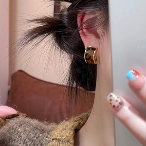 Close-up of leopard print C-shape earrings with gold edges worn by a female model