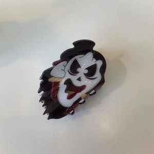 Detailed view of a black ghost hair claw clip with white skull face for Halloween hair styling