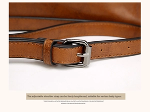 Detail of adjustable brown leather shoulder strap with dark metal buckle and lychee texture