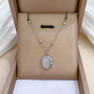 Elegant rotating cat eye stone necklace with gold finish rope texture on a beige jewelry box