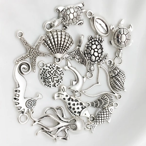 Detailed view of silver sea turtle, starfish, and seashell alloy charms for DIY jewelry