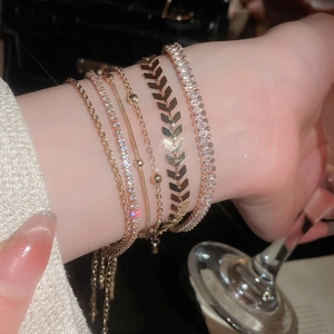 Close-up of five-piece gold bracelet set with sparkling cubic zirconia on female wrist