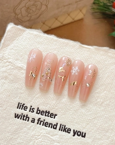 Close-up of nude pink Christmas nail stickers featuring gold snowflakes and white snowmen
