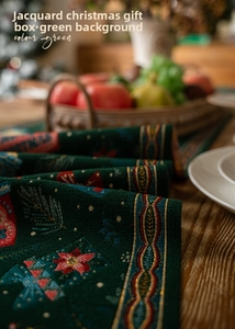 Detail of green Christmas table runner featuring jacquard gift boxes and floral patterns