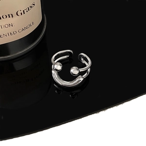 Silver double-layer open smile face ring with metal beads on a black reflective surface