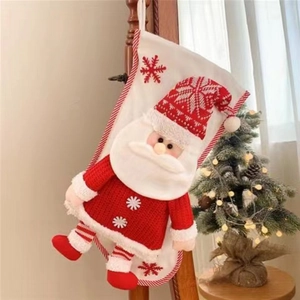 Large knitted Christmas stocking with a 3D Santa Claus figure hanging on a wooden chair