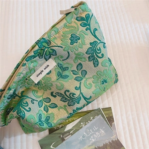Macro view of green floral jacquard fabric vanity bag with simple wish label