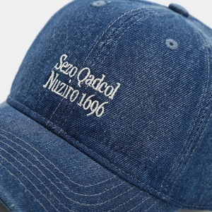 Macro shot of high-quality white embroidery on dark blue washed denim baseball cap