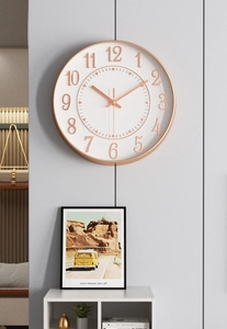 Detail of a 12-inch rose gold wall clock on a minimalist grey living room wall