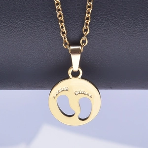 Macro shot of polished 18k gold plated stainless steel disc pendant with baby footprints