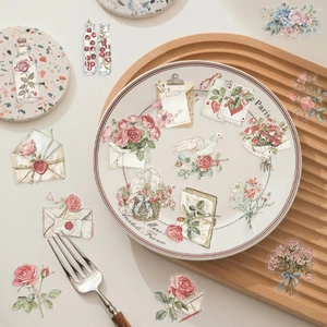 Detailed view of vintage flower and envelope stickers on a ceramic plate for journaling