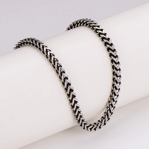 Polished silver wheat chain necklace for men displayed on a professional white stand