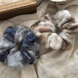 Gros plan de chouchous en mohair doux bleu-gris et beige-marron sur lin texturé