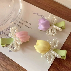 Detailed view of handmade tulip hair clips with pearls on elegant white card display