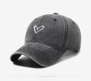 Detailed side view of washed dark grey baseball cap featuring white heart embroidery