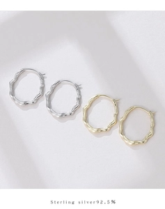 Macro shot of S925 sterling silver hoop earrings with irregular wave texture in gold and silver