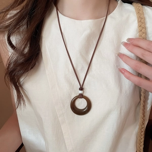 Vue détaillée du pendentif rond creux en acrylique brun sur un mannequin en haut en lin