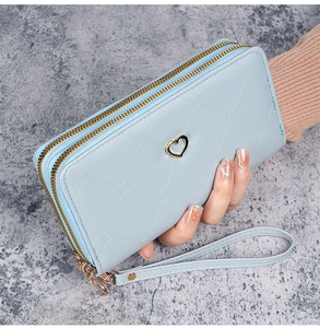 Close-up of light blue long wallet with dual zippers and golden heart ornament detail
