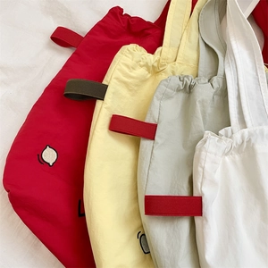 Primo piano di borse tote in tela colorata rossa, gialla, verde e bianca con ricamo