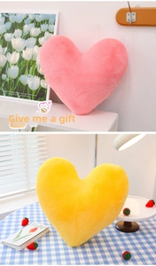 Detail of plush heart-shaped decorative pillows in soft pink and yellow faux fur textures