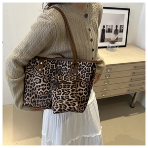Detailed shot of leopard print tote bag with brown leather straps on a model