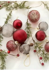 Close-up of ribbed red and gray glass Christmas ornaments with pine cones on white