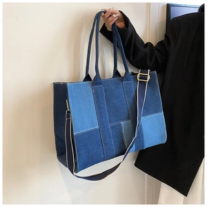 Detail of denim patchwork tote bag with white stitching and adjustable shoulder strap