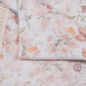 Detailed macro view of floral cotton gauze baby blanket with delicate crochet lace trim